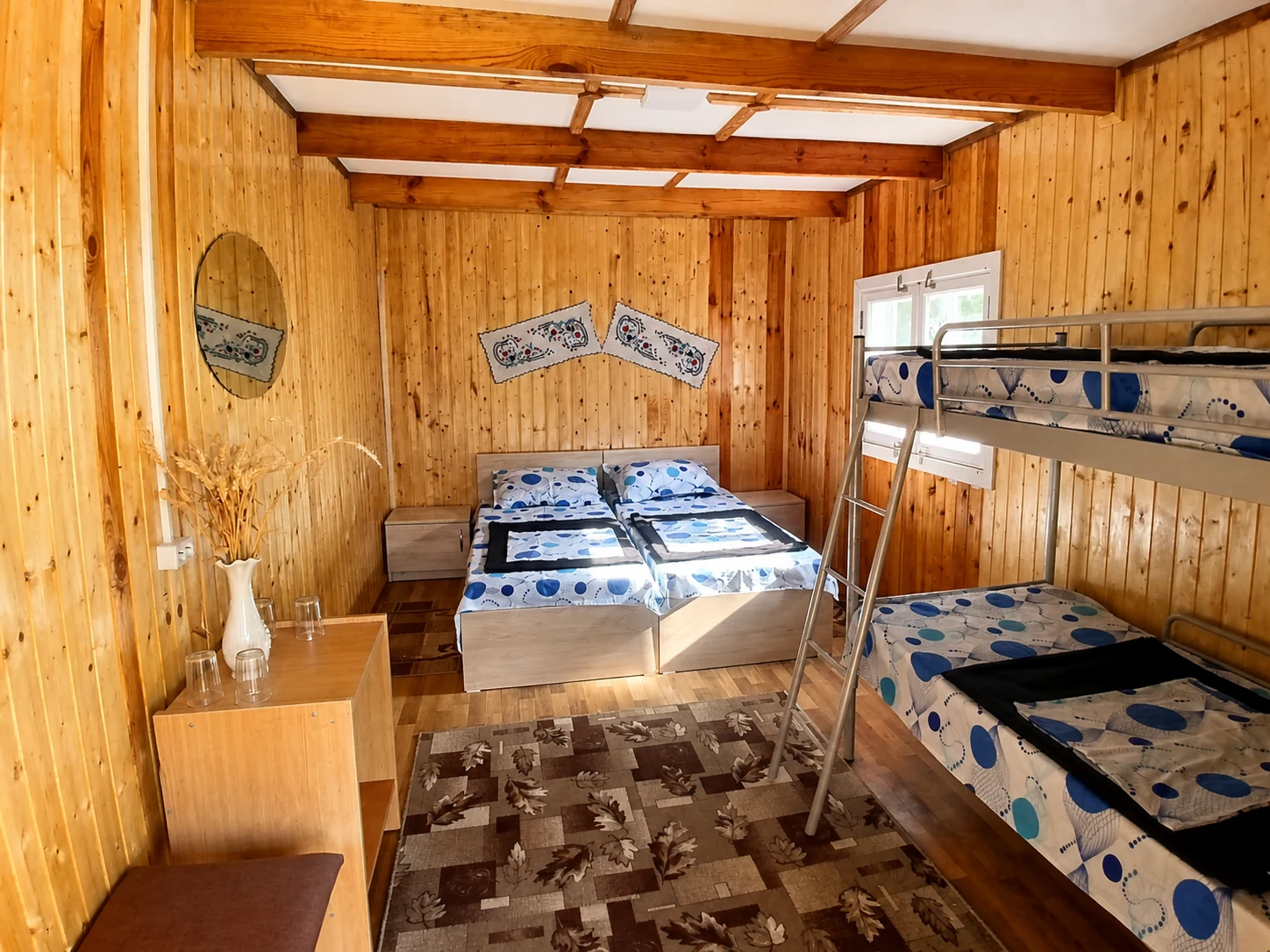 Vedere largă a camerei private cu baie comună, cu toate paturile și finisajele din lemn